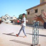 A group of youngsters playing cricket on road