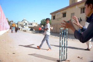 A group of youngsters playing cricket on road