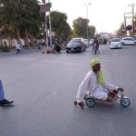 Traffic police officials assist a disabled person in crossing Club Chowk by stopping the traffic
