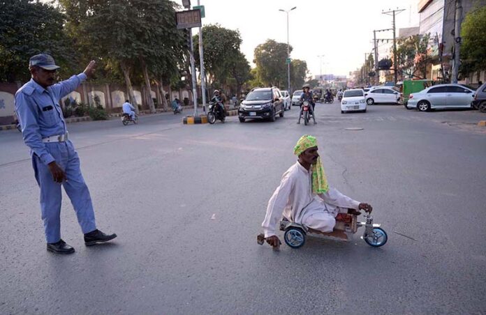 Traffic police officials assist a disabled person in crossing Club Chowk by stopping the traffic