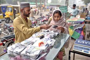 A young girl purchases a face mask at a stall in Shaheen Chowk, highlighting public health awareness amid air quality concerns.