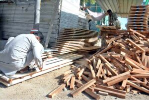 A carpenter skillfully shapes wood into wooden framework, demonstrating expert craftsmanship in the process of constructing a building in the city.
