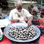 A vendor is busy displaying seasonal fruit Singhara to attract customers at his hand cart setup