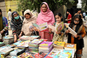Families selecting and purchasing old books from a roadside stall at Mall Road in the city