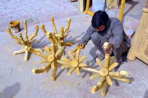 A skilled worker colours hanging stand at Shahdara Furniture Market