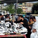 People selecting and purchasing used shoes from roadside vendor