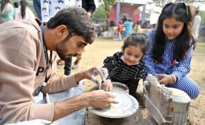 A little girl eagerly touches a doll on display at Lok Mela, Lok Virsa.