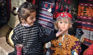 A little girl eagerly touches a doll on display at Lok Mela, Lok Virsa.