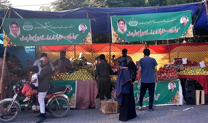 People buying fruits from stalls at Sahulat Sasta Bazar, organized by the Punjab government