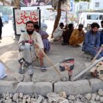 Laborers sit with their tools during the hot days, waiting for work at the roadside to earn a livelihood in the provincial capital