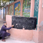 School staff writes a notice announcing the closure of schools till November 17,due to rising smog in the provincial capital, outside Sodiwal Girls High School in Provincial Capital