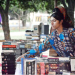 A woman selecting a book from old book stall setup in Frere Hall
