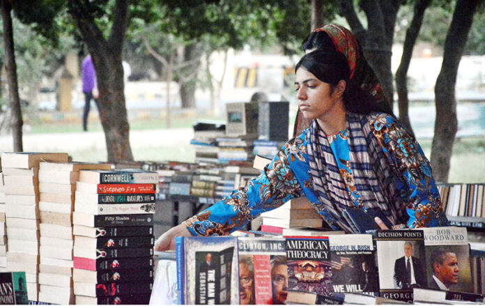 A woman selecting a book from old book stall setup in Frere Hall