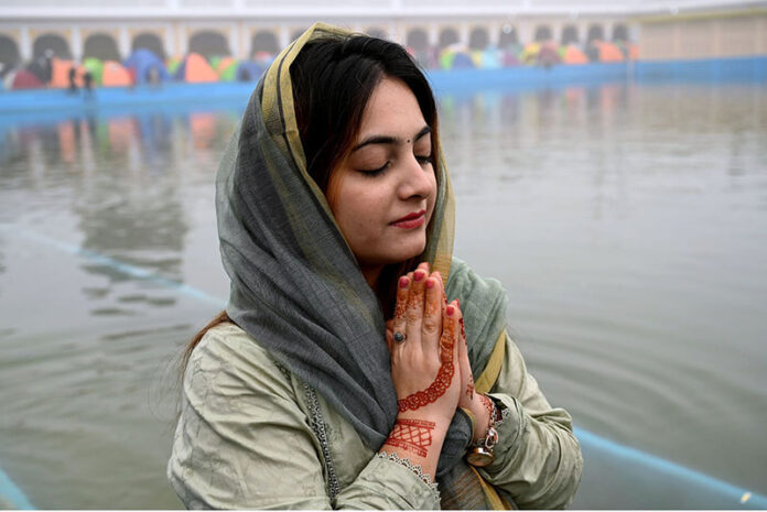 A female Sikh pilgrim prays as Sikh community gathers in reverence, marking the 555th birth anniversary of Guru Nanak Dev and honoring his legacy of peace and equality