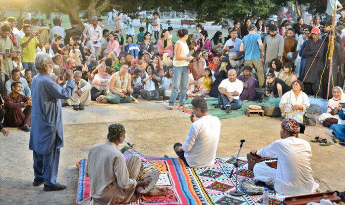 Visitors listening to folk music organized by Pakistan Fisher Folk Forum under Fourth Karachi Biennale 2024 in Frere Hall