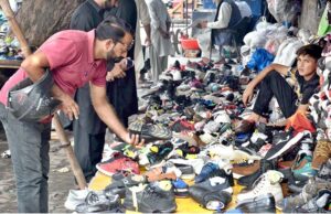 A man buying second-hand branded shoes from a roadside vendor.