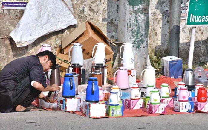 Vendor displaying and arrange utensils for customers' attention at Mudassar Shaheed Road