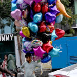 A street vendor waits for customers to buy balloons, striving to support his family at super market in Federal Capital