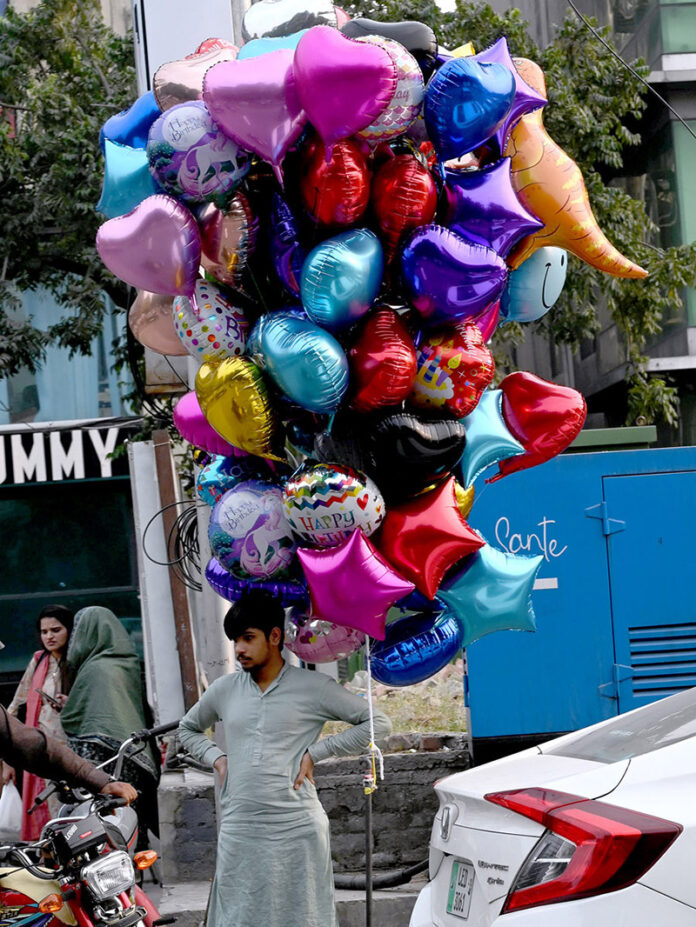 A street vendor waits for customers to buy balloons, striving to support his family at super market in Federal Capital