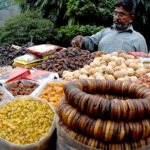 A vendor arranges seasonal dry fruits at his roadside stall, attracting customers as demand rises with the dropping temperatures in the provincial capital