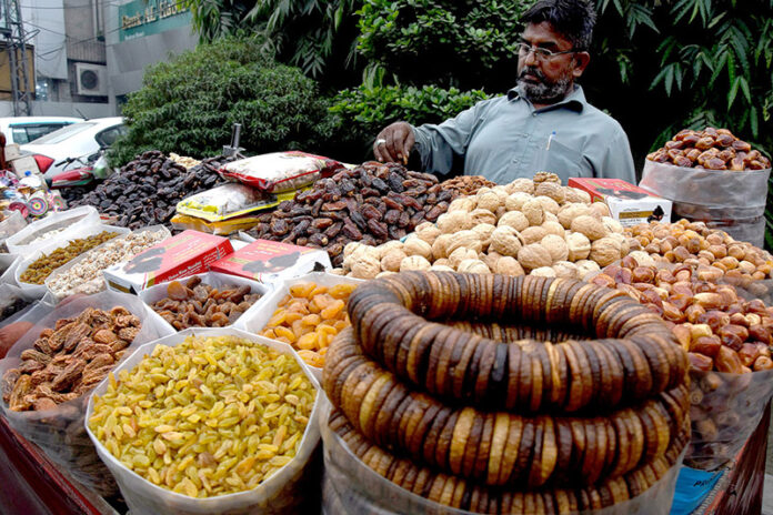 A vendor arranges seasonal dry fruits at his roadside stall, attracting customers as demand rises with the dropping temperatures in the provincial capital