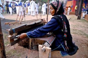 A woman weaves a mat by hand on the frame during the opening ceremony of the 'Annual Ten-Day Folk Festival Lok Mela' at Lok Virsa in the federal capital