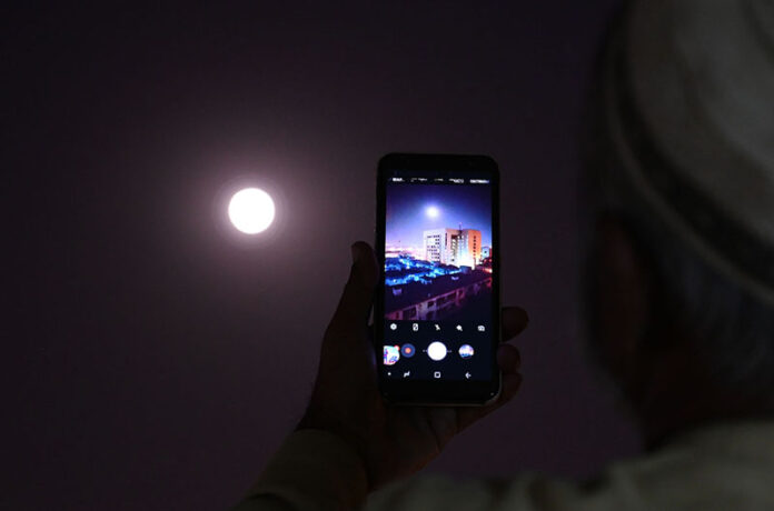 A man frames the full moon on his smartphone in the Provincial Capital