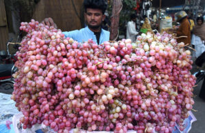 A vendor displaying seasonal fruit Grapes to attract the customers on his handcart at a local market in the city