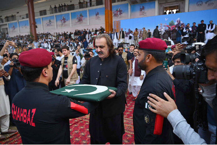 A paratrooper commander presents the national flag to Chief Minister KP, Ali Amin Gandapur, at a horse and cattle show organized by the Directorate General of Sports Khyber Pakhtunkhwa at Col Sher Khan Stadium