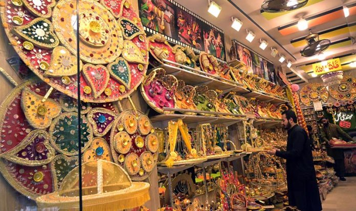 A vendor busy in displaying henna stuffs to be used in weddings at his shop at Old Fort in the city