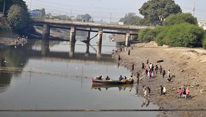 Large number children and fisherman catching the fishes at Phuleli canal during annual cleaning of the canal from Sindh irrigation department