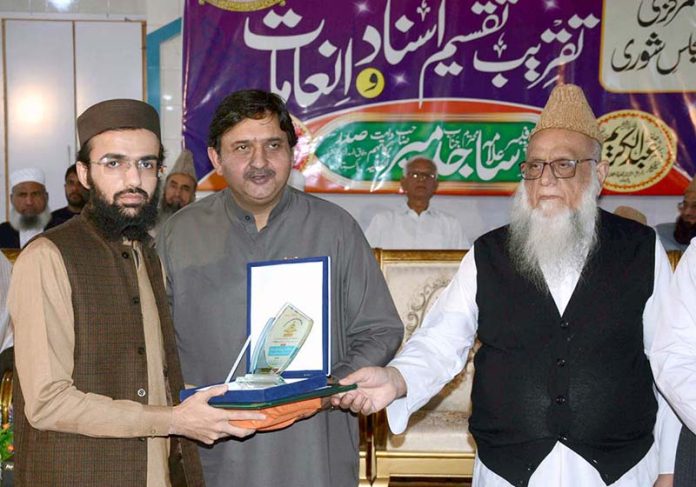 Speaker Punjab Assembly Malik Ahmad Khan is distributing prizes and certificates during a ceremony in Jamia Salfia