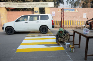 A painter is busy painting the Zebra crossing line to stop vehicles for Students crossing the road in front of the Wilayat Hussain Islamia Graduate College at Masoom Shah Road
