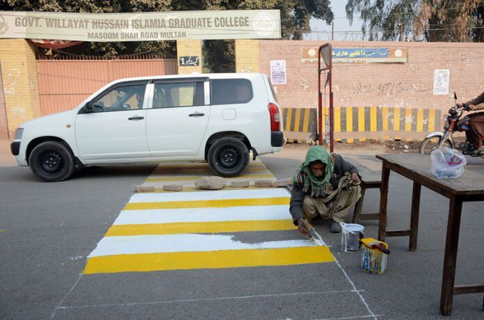 A painter is busy painting the Zebra crossing line to stop vehicles for Students crossing the road in front of the Wilayat Hussain Islamia Graduate College at Masoom Shah Road