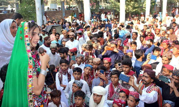 Folk singer performing Sindhi song during celebration of Sindhi Ajrak Topi Culture Day at Sindh Museum