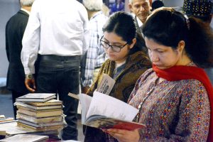 Female visitors browse books at a stall during the 17th International Alami Urdu Conference at the Arts Council of Pakistan