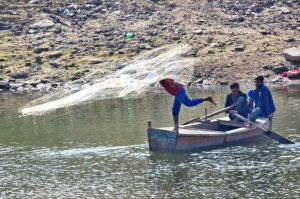The fisherman is throwing a net in Pinyari Canal to catch fish from the boat.