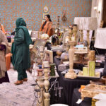 Women visiting stalls at an art exhibition organized by Andleeb Ghalib, showcasing the strength, creativity, and empowerment of women through art at a local hotel