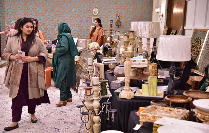Women visiting stalls at an art exhibition organized by Andleeb Ghalib, showcasing the strength, creativity, and empowerment of women through art at a local hotel