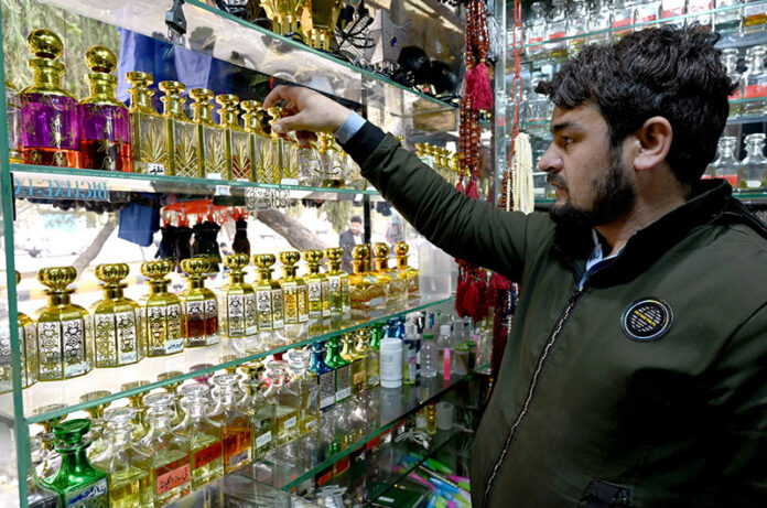 A shopkeeper arranging and displaying perfumes to attract the customers at his shop in the Aabpara Federal Capital