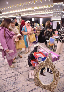 Women visiting stalls at an art exhibition organized by Andleeb Ghalib, showcasing the strength, creativity, and empowerment of women through art at a local hotel