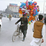 A vendor on the way along with bicycle loaded with different shapes air-filled balloons to attract customers at KhannaPul