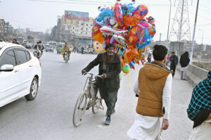 A vendor on the way along with bicycle loaded with different shapes air-filled balloons to attract customers at KhannaPul