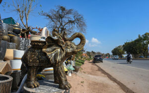 A vendor displays a majestic elephant statue along with other decorative items to attract customers at the roadside