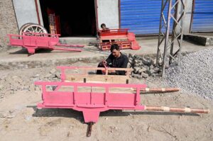 Workers busy in coloring new donkey carts at his workplace.
