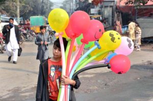 A young vendor waiting for customers to sell colorful balloons.