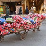 A laborer pulling handcart loaded with pillows to deliver in a local market