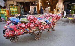 A laborer pulling handcart loaded with pillows to deliver in a local market