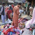Women busy selecting and purchasing pieces of cloth from a stall at Shaheen Chowk