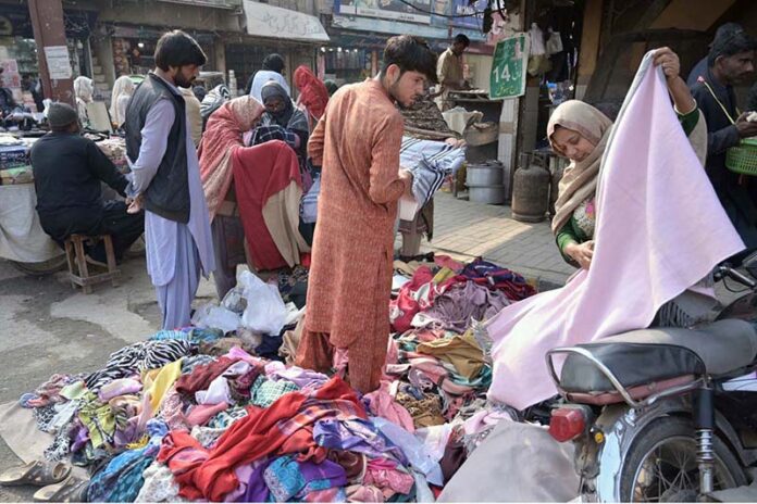 Women busy selecting and purchasing pieces of cloth from a stall at Shaheen Chowk